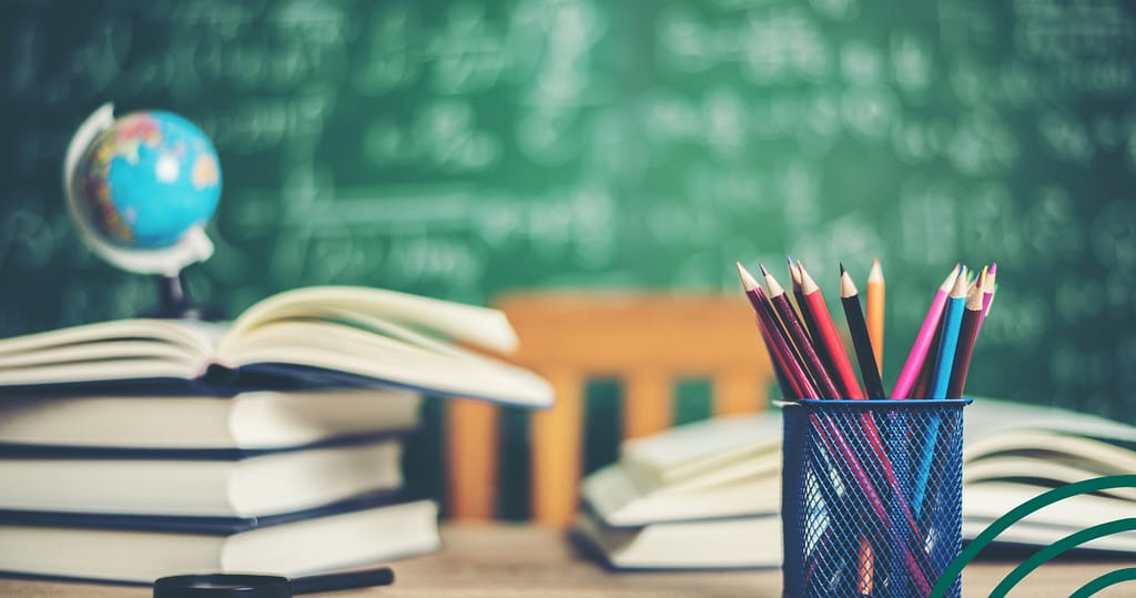 Classroom with pencils and a globe, teachers desk with books for side income for teachers