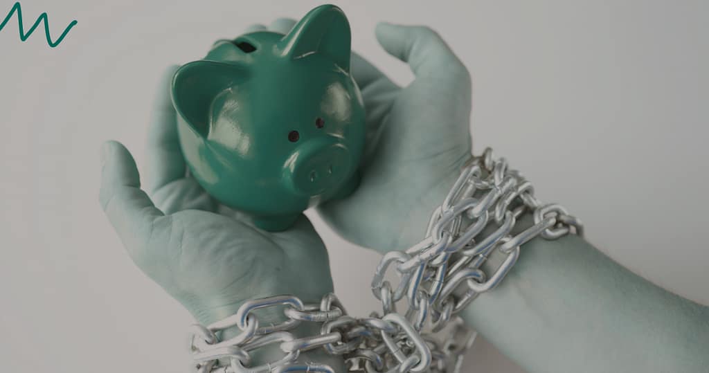 Hands bound by chains holding a green piggy bank, symbolizing debt traps and the importance of avoiding predatory loans