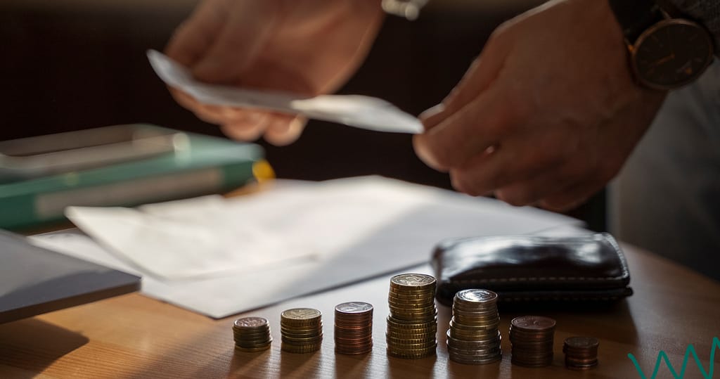 Stacked coins on a desk with a person handling documents, symbolizing financial responsibility and your rights as a borrower.