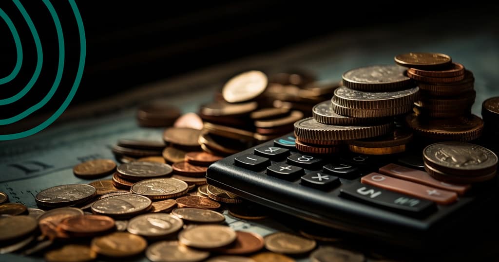 Close-up of stacked coins and a calculator on top of dollar bills, symbolizing the true cost of a loan including APR and fees.