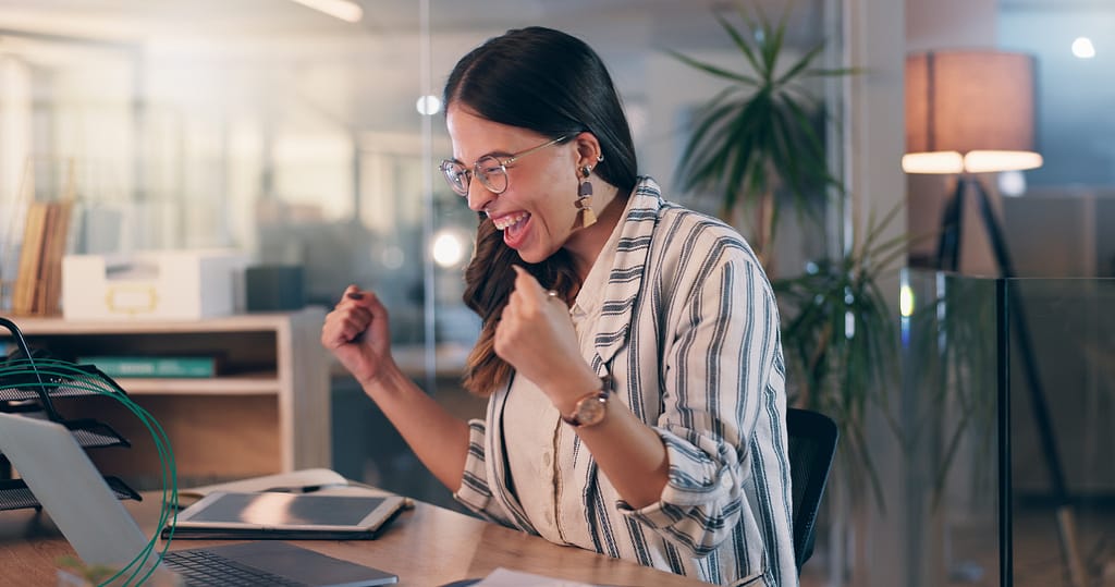 Excited young woman celebrating success at her desk after improving her credit score
