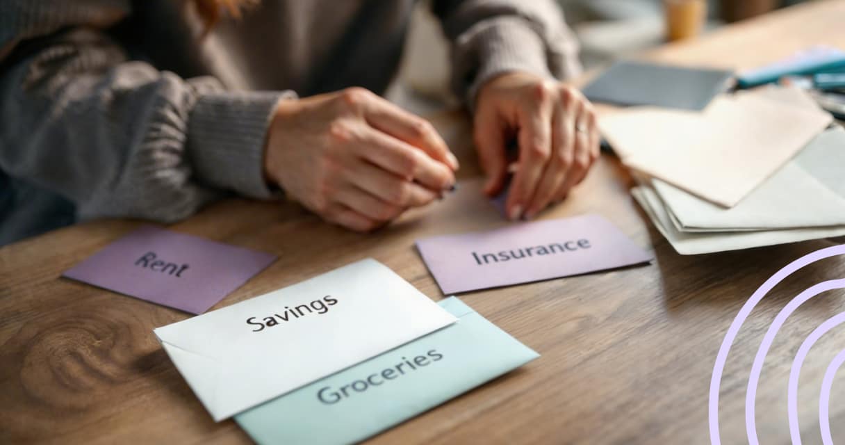 Person organizing budget envelopes labeled rent, savings, groceries, and insurance to plan paycheck spending